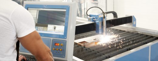 Selective focus of procss of plasma cutting on metal factory. Strong muscular male welder working with computer and controlling production process. Concept of sparks and cnc.